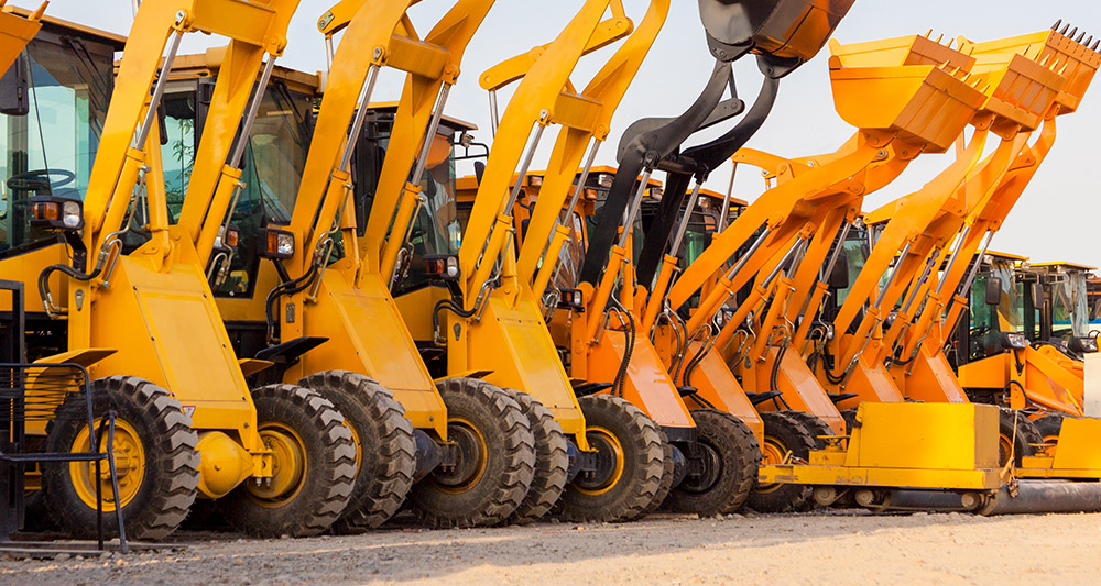 line of heavy duty off highway machine with buckets raised in the air